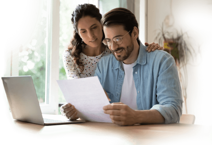 Couple reviewing tax documents together at home with laptop